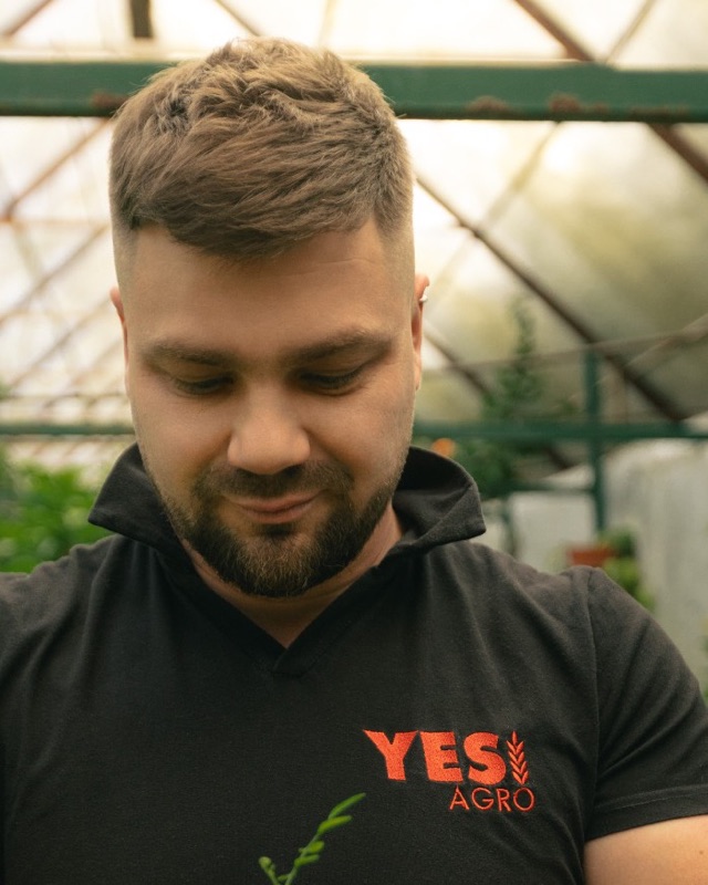 Anton Shilenko, head of YES!AGRO, holding a seedling in a greenhouse